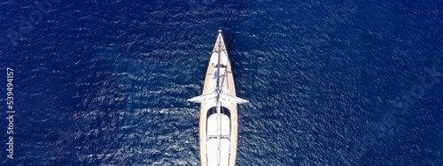 Aerial drone ultra wide panoramic photo with copy space of beautiful sail boat anchored in deep blue open ocean sea