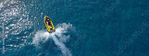 Aerial drone ultra wide top down photo with copy space of watercraft cruising in low speed in deep blue calm sea