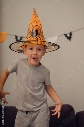Boy in orange halloween hat with spider making funny and scary faces, halloween concept. High quality photo