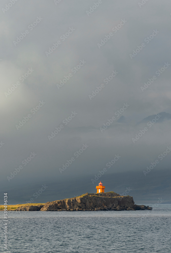 The bright-orange Aeoarstein Lighthouse in Djupivogur, east Iceland, sits atop harsh volcanic rock