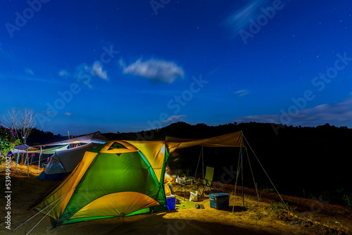 The image of camping tents  in the night with stars and blue sky.  Khao Thewada, Phu toei National Park, Thailand.