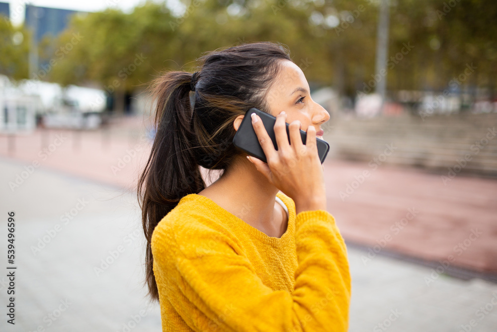 Side of happy young woman talking with cellphone outdoor Side of happy young woman talking with cellphone outdoor
