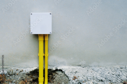 Fotografi White PVC plastic box for building electric junction with yellow pipe at concret