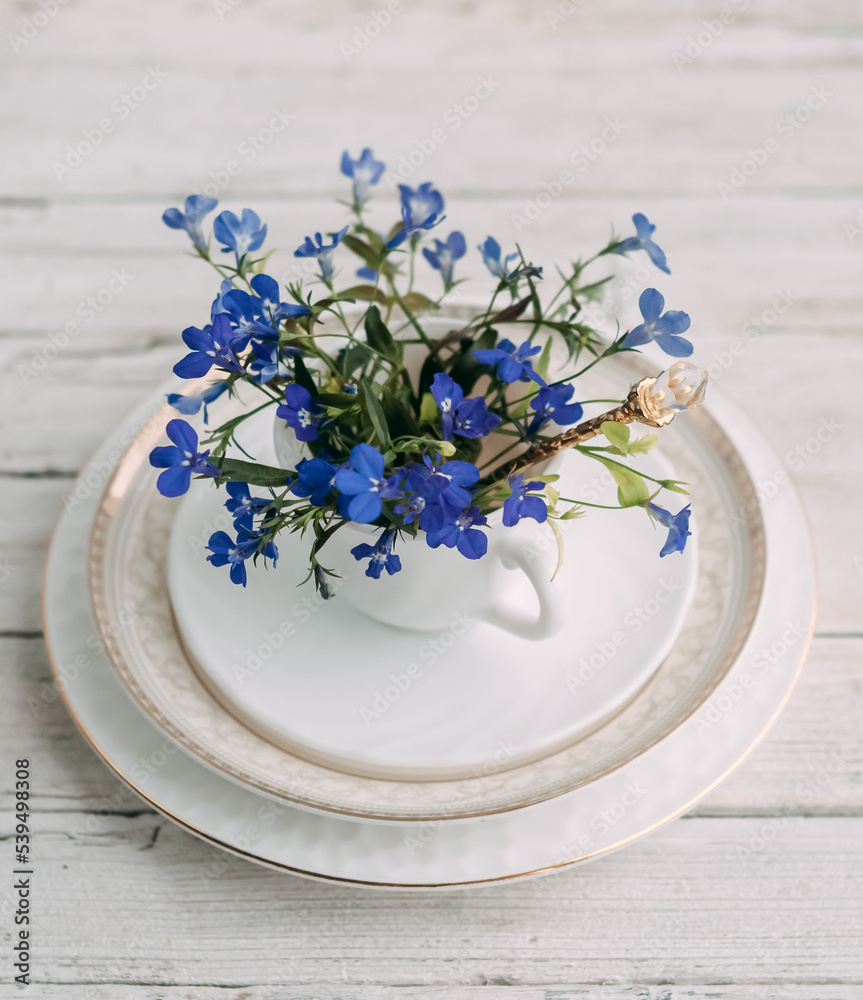 blue lobelia flowers in a white cup on a wooden background