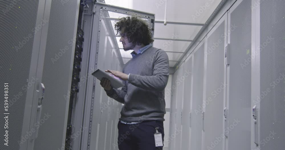 IT engineer or data science specialist working on tablet computer in server room at a modern cloud computing virtual data center supercomputer. IT engineer or data science specialist working on tablet computer in server room at a modern cloud computing virtual data center supercomputer.