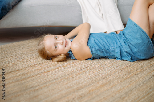 little girl is playing lying on the floor in the living room . photo