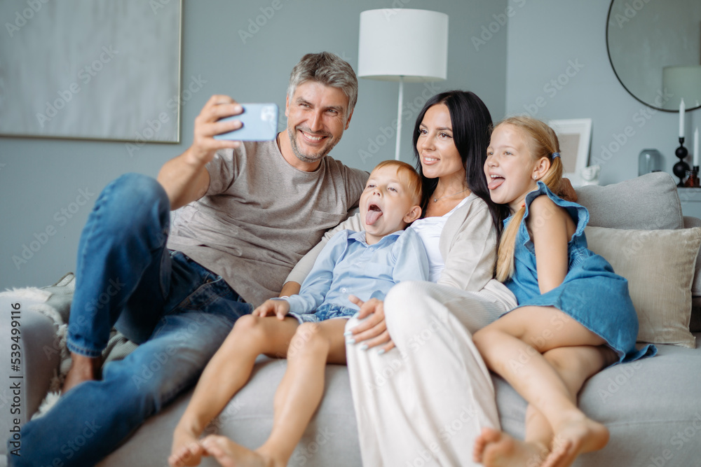 happy family with kids having fun taking selfies sitting on the couch.