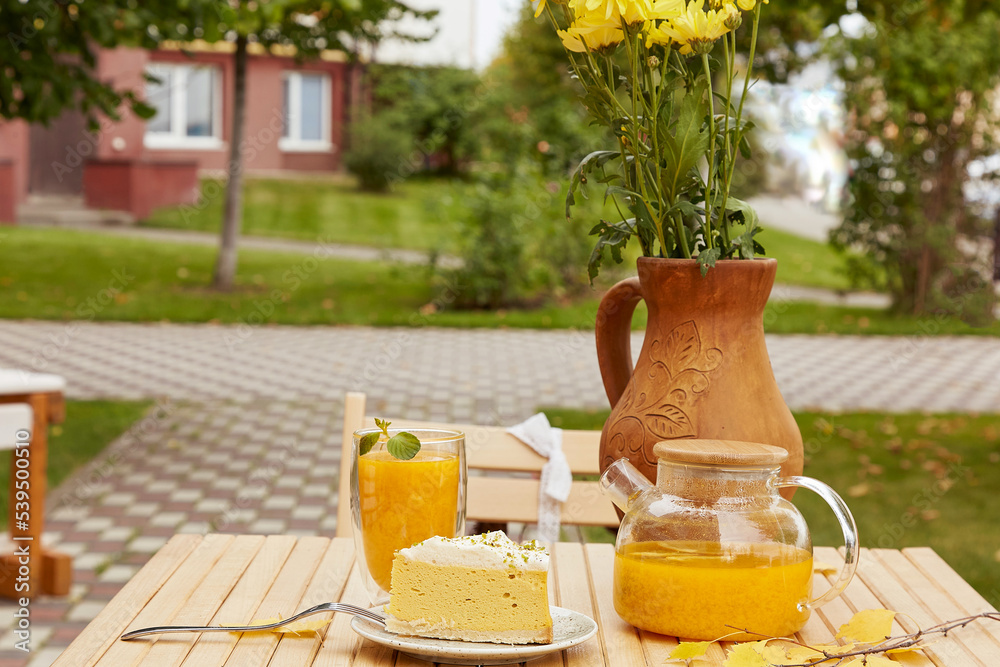 Fototapeta premium Aesthetic autumn breakfast with healthy sea buckthorn tea and vegan pumpkin cake dessert. Organic increased immunity herbal tea