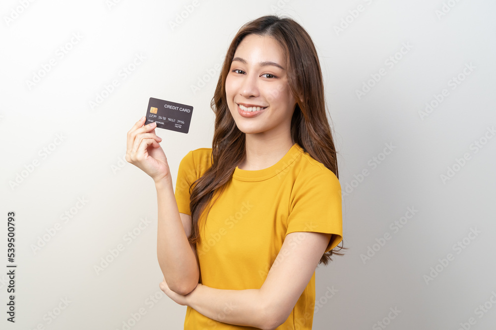Happy Young asian woman smiling and holding credit card isolated on background Happy Young asian woman smiling and holding credit card isolated on background