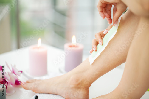 Close-up Of Woman Waxing Her Leg at home bathroom