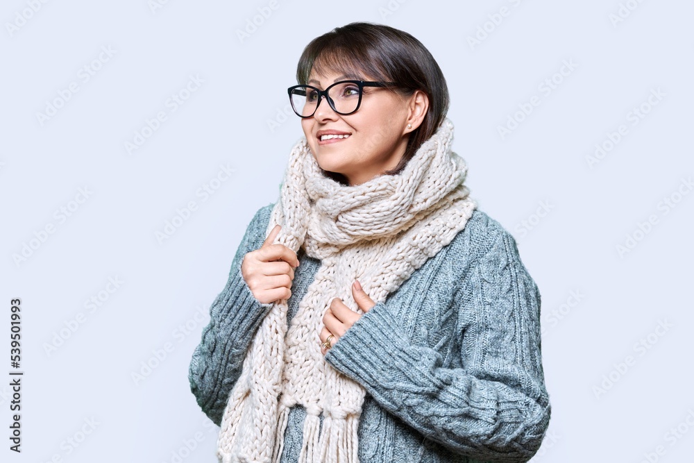 Winter portrait of mature woman in warm clothes on light background Winter portrait of mature woman in warm clothes on light background