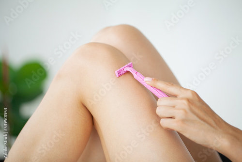 Close up of woman shaving legs in bathroom