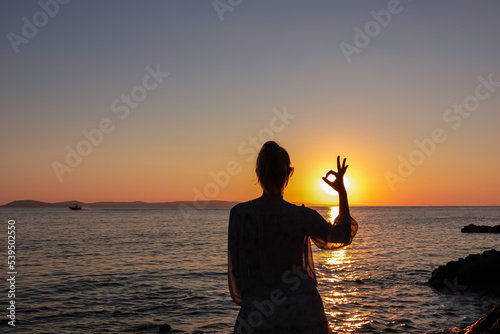Silhouette of tourist woman with panoramic view of sunset over Aegean Mediterranean Sea on Karydi beach, peninsula Sithonia, Chalkidiki (Halkidiki), Greece, Europe. Romantic atmosphere, sea reflection photo