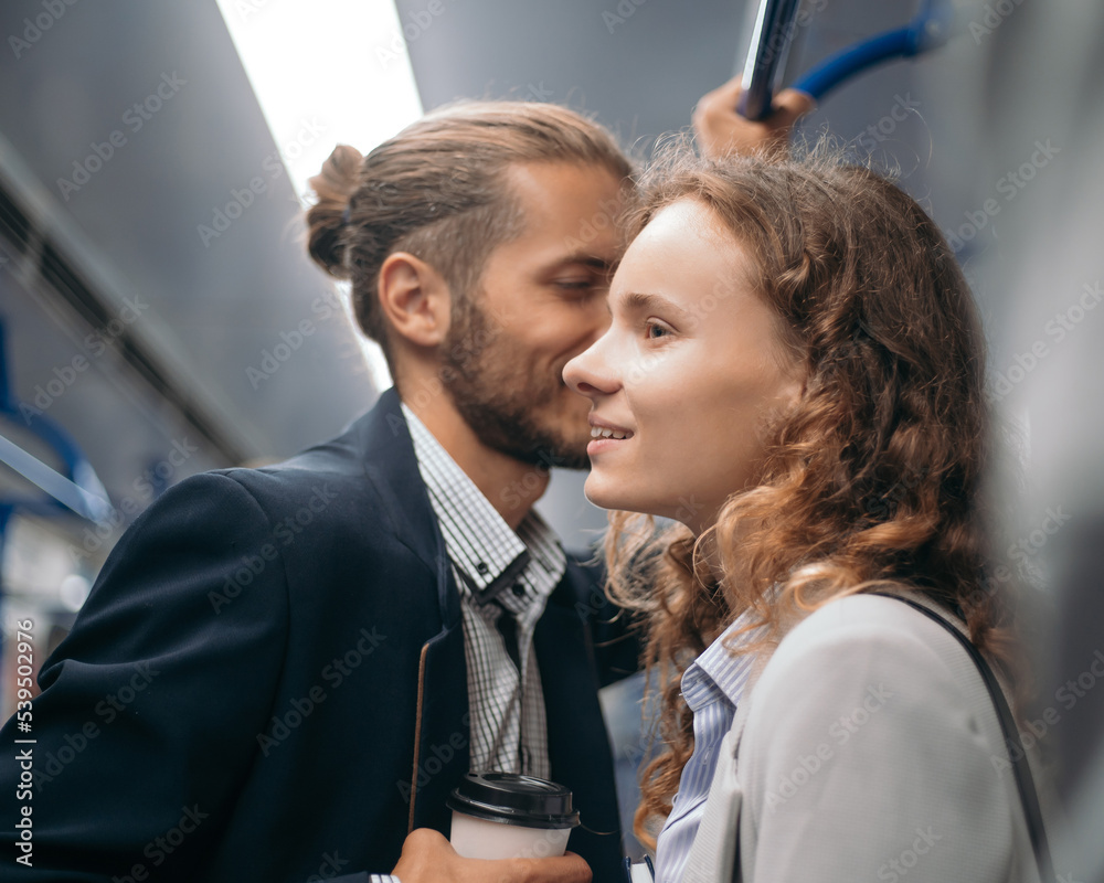 beautiful couple rides standing in a subway car.