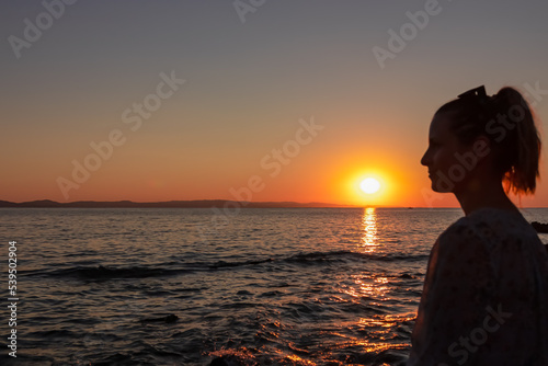 Silhouette of tourist woman holding the sun with panoramic view of sunset over Aegean Mediterranean Sea on Karydi beach  peninsula Sithonia  Chalkidiki  Halkidiki   Greece  Europe. Romantic atmosphere