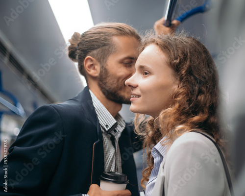 beautiful couple rides standing in a subway car.