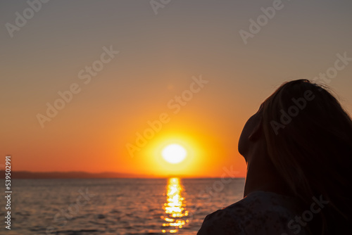 Silhouette of tourist woman holding the sun with panoramic view of sunset over Aegean Mediterranean Sea on Karydi beach, peninsula Sithonia, Chalkidiki (Halkidiki), Greece, Europe. Romantic atmosphere