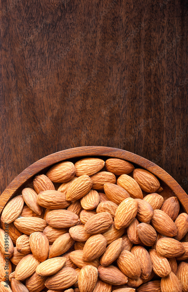 Almonds in a wooden tray on a rustic wooden floor with copy space, close up, flat lay. Almonds in a wooden tray on a rustic wooden floor with copy space, close up, flat lay.