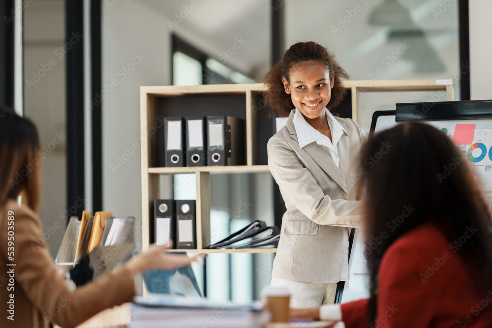 Fototapeta premium African businesswoman giving presentation on flip chart discussing new marketing research results with executive team in boardroom, black employee reporting about project at meeting