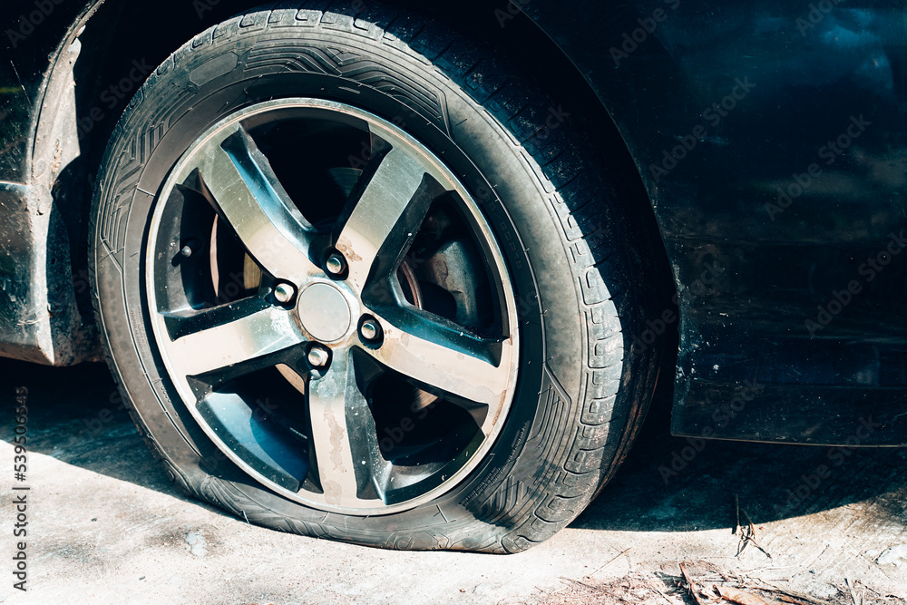 Close up of a car flat tire, air tire pressure lose on the road.

