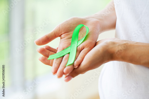 Young woman holding awareness green ribbon as a symbol to awareness Lymphoma cancer photo