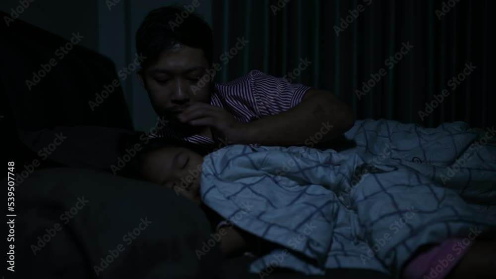 Dad and daughter sleep on the bed in bedroom,Watch cartoon with phone,Father day concept,Single dad,listen tale before sleep Dad and daughter sleep on the bed in bedroom,Watch cartoon with phone,Father day concept,Single dad,listen tale before sleep