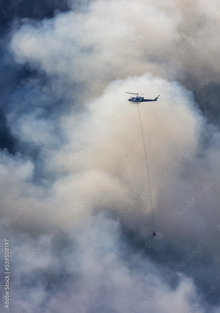 Wildfire Service Helicopter flying over BC Forest Fire and Smoke on the mountain near Hope during a hot sunny summer day. British Columbia, Canada. Natural Disaster Wildfire Service Helicopter flying over BC Forest Fire and Smoke on the mountain near Hope during a hot sunny summer day. British Columbia, Canada. Natural Disaster