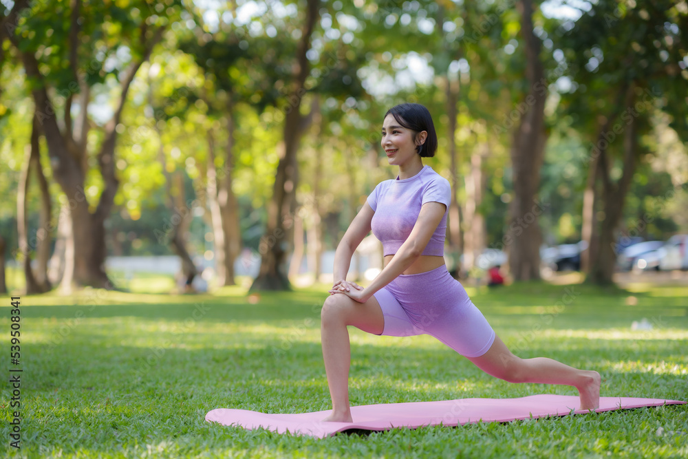 Fototapeta premium Yoga in the park. Young Asian woman practicing yoga pose at the park.