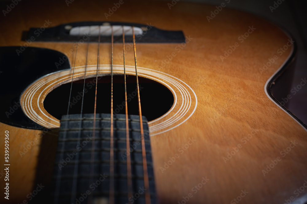 Close-up and details of old acoustic guitar, Line and curve of instrument, Selective focus of guitar strings with fretboard and neck, Musical concept, Guitar background Close-up and details of old acoustic guitar, Line and curve of instrument, Selective focus of guitar strings with fretboard and neck, Musical concept, Guitar background