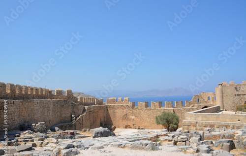 ancient wall of fortress with ruins and blue sky on horizon, Greece
