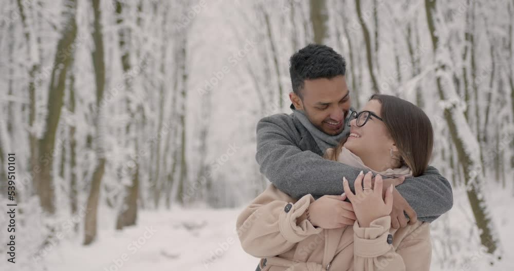 Multiethnic couple hugging each other in winter forest Multiethnic couple hugging each other in winter forest