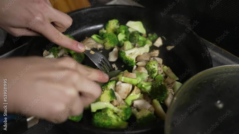 A woman cooks broccoli with mushrooms in a pan, cooks food on a gas stove A woman cooks broccoli with mushrooms in a pan, cooks food on a gas stove