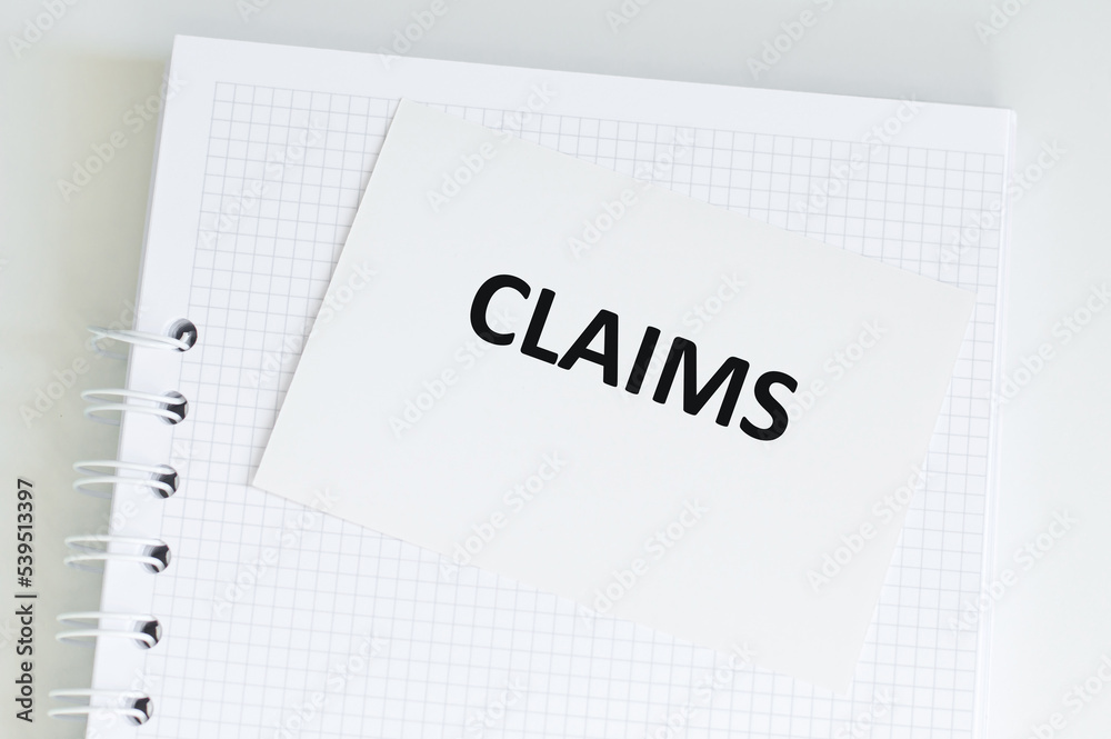 White card with CLAIMS text on a notebook on the table, medical concept White card with CLAIMS text on a notebook on the table, medical concept