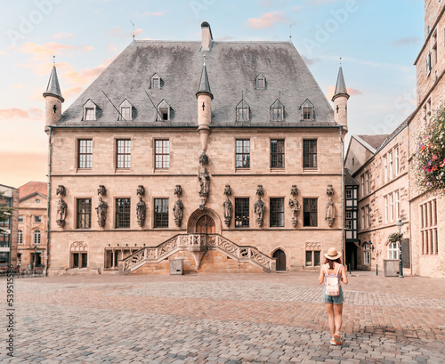 Happy woman tourist walking with backpack and enjoying panorama of the city hall rathaus and market square of the old town of Osnabruck in Germany