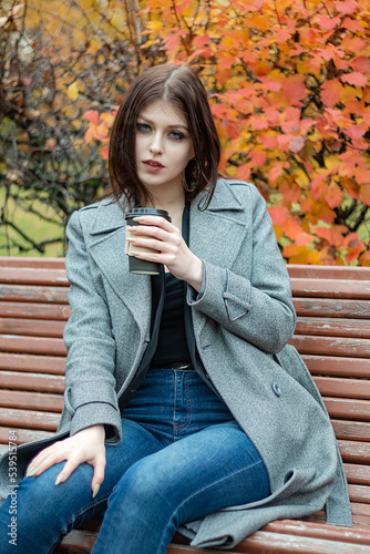 Girl with a cup of coffee in the autumn park.