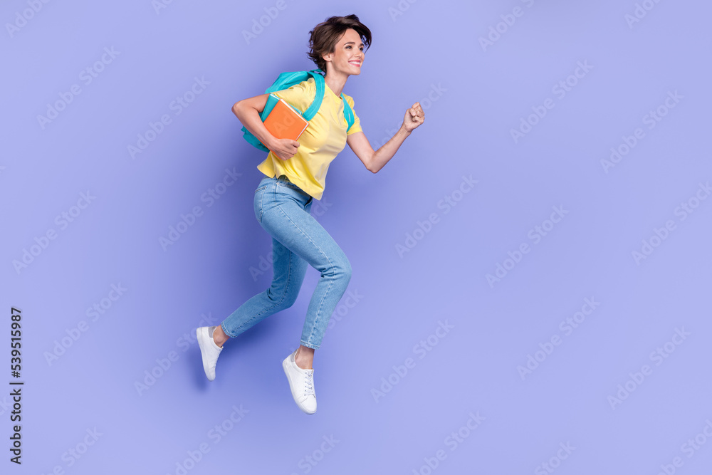 Full length portrait of carefree active person carry bag hold book jump rush isolated on purple color background