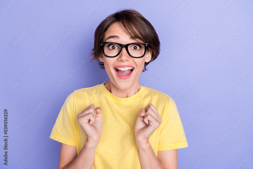 Closeup photo of young attractive pretty nice woman wear yellow t-shirt eyeglasses crazy unexpected raise fists reaction isolated on pastel purple color background Closeup photo of young attractive pretty nice woman wear yellow t-shirt eyeglasses crazy unexpected raise fists reaction isolated on pastel purple color background