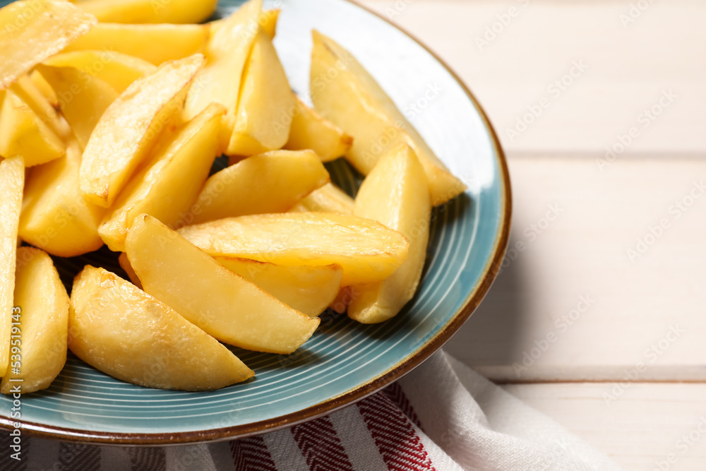 Plate with tasty baked potato wedges on white wooden table, closeup Plate with tasty baked potato wedges on white wooden table, closeup