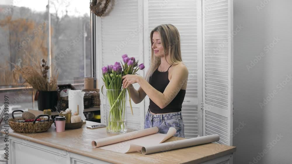 A young beautiful woman engaged in floristry begins to collect the best flowers for her flower arrangement. Floristry A young beautiful woman engaged in floristry begins to collect the best flowers for her flower arrangement. Floristry