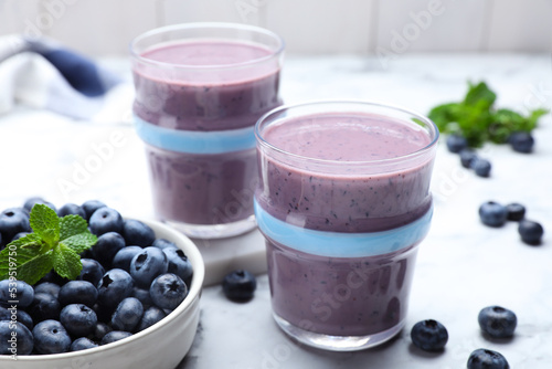 Tasty blueberry smoothie with mint and fresh berries on white marble table
