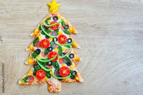 Christmas tree pizza on wooden background.Creative art food idea for celebrate Christmas.Top view.Copy space