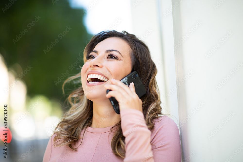smiling young woman talking with cellphone by white wall smiling young woman talking with cellphone by white wall