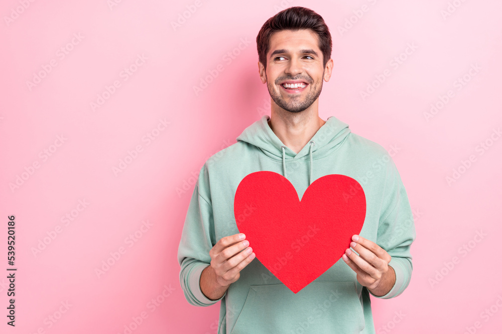 Photo of young attractive handsome man looking empty space dreaming abouy his girlfriend hold red paper heart isolated on bright pink color background Photo of young attractive handsome man looking empty space dreaming abouy his girlfriend hold red paper heart isolated on bright pink color background