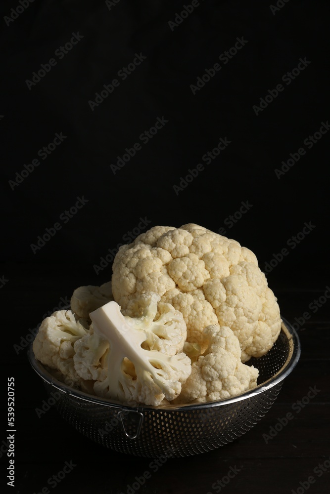 Colander with fresh raw cauliflower on black wooden table Colander with fresh raw cauliflower on black wooden table