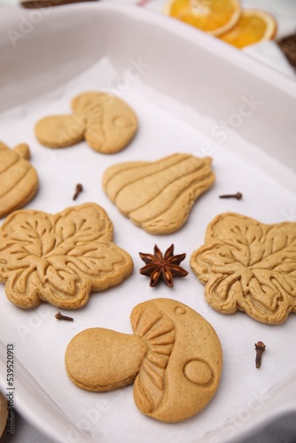 Different tasty cookies and spices on white parchment