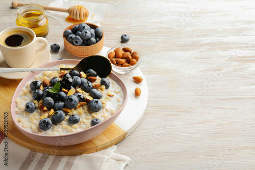 Healthy oatmeal porridge and ingredients served on wooden table. Space for text