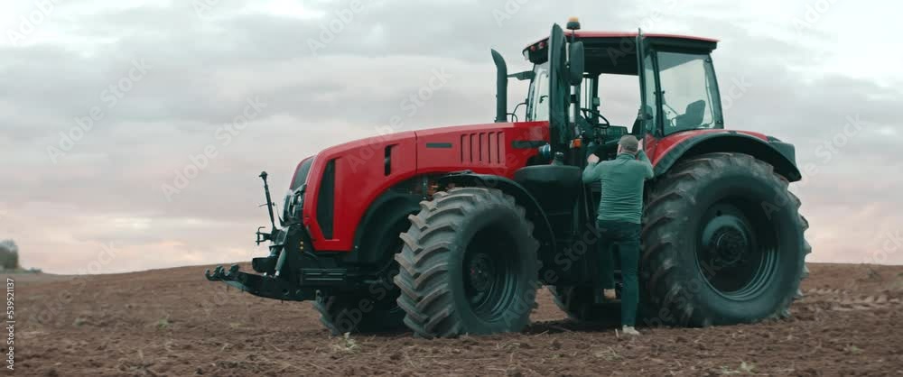 Hero shot portrait of 50s farmer walking towards tractor early in the morning in the field. Shot with 2x anamorphic lens