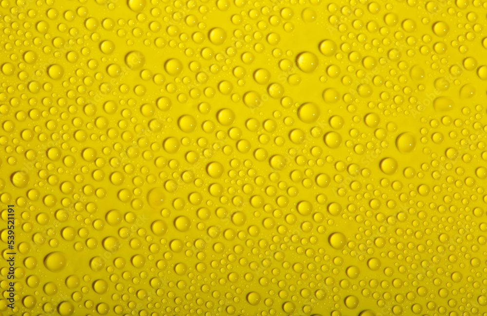 Water drops on glass as a background. Condensation on a cold drink. Yellow background with drops texture. Water drops on glass as a background. Condensation on a cold drink. Yellow background with drops texture.