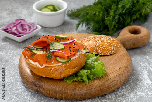 Vegan Carrot Lox served on bread bun with cream cheese, cucumber slices, red onion and dill. Tasty plant-based fish replacement to traditional lox made with strips of marinated carrots. photo