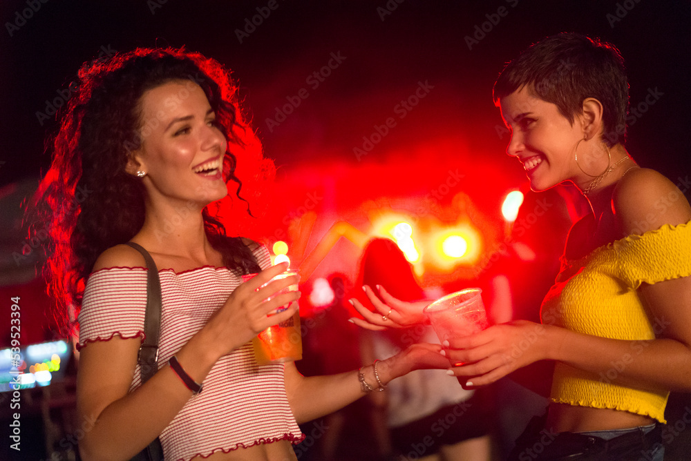 Two happy young girls dancing and drinking beer on the party concert in the night club Two happy young girls dancing and drinking beer on the party concert in the night club